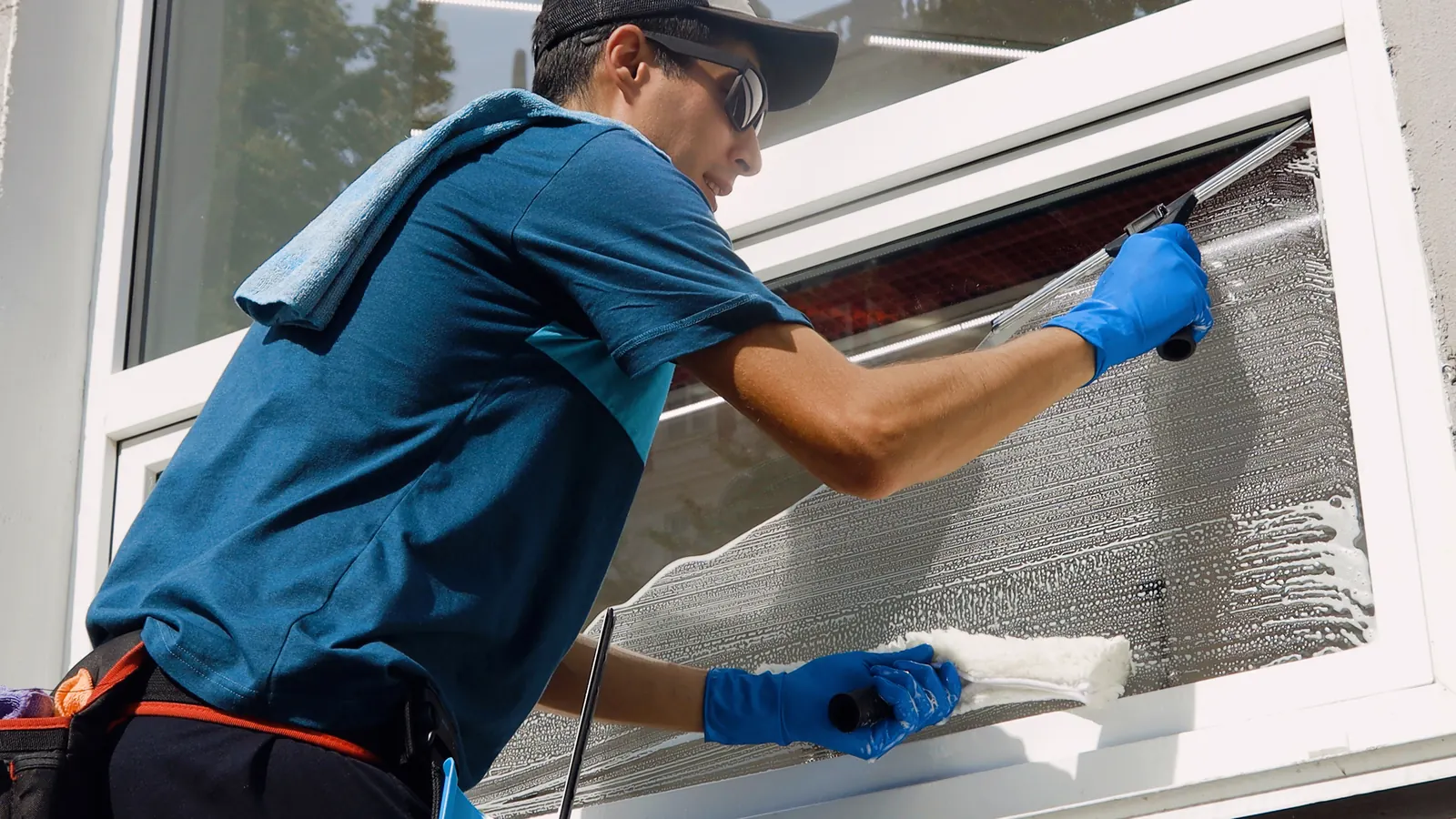 Fensterputzer reinigt ein Fenster mit Einwascher und Abzieher