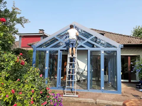 Fensterputzer auf der Leiter reinigt das Glasdach eines Wintergartens