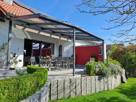 Terrassendach aus Glas mit Unterdachmarkise an einem Einfamilienhaus